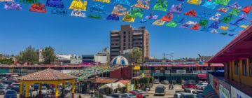 View of a colorful market in Tijuana with a large building in the background - Best Call Center in Tijuana.