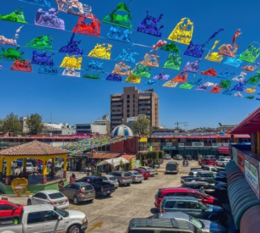View of a colorful market in Tijuana with a large building in the background - Best Call Center in Tijuana.