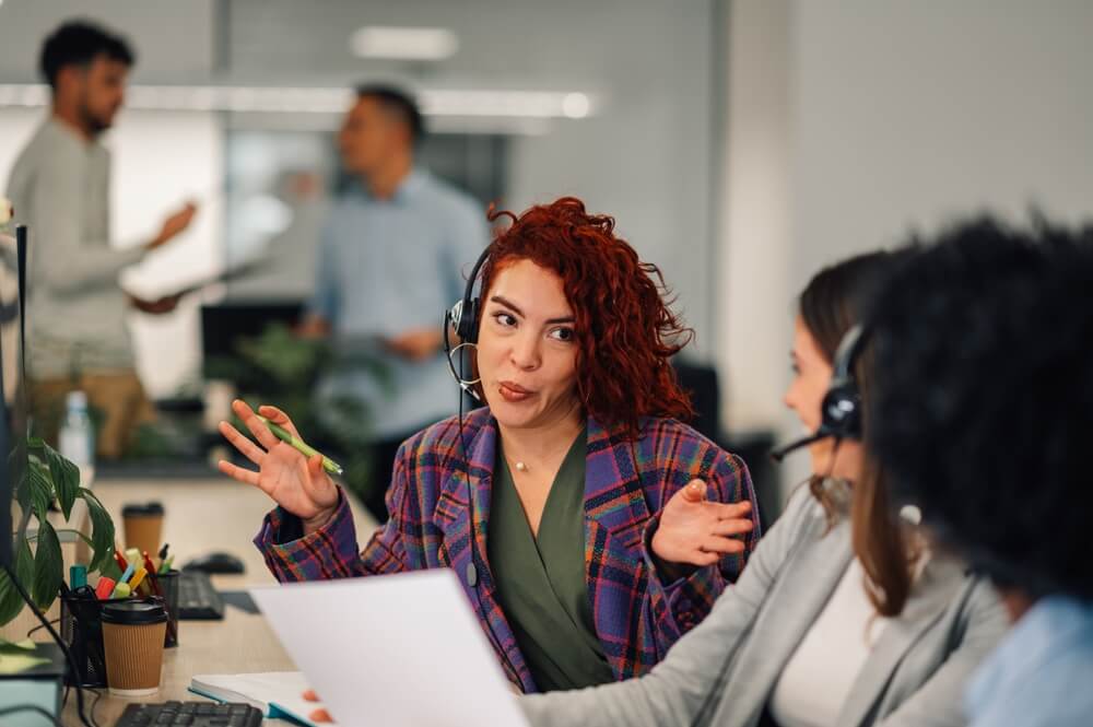 Call center agent in Tijuana chatting with friends and colleagues, laughing in a happy environment
